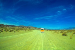 Yellow bus driving through desert.