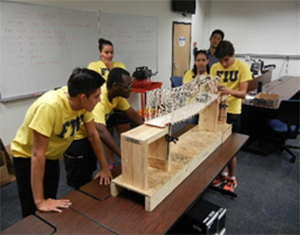 Using remote control toy cars, students at FIU’s transportation camp test their balsa-wood bridge